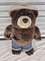Front view of Smokey Bear plush wearing hat, jeans, belt, holding shovel