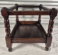 overall view of wooden magazine stand showing turned legs and lower tray