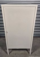 Front view of closed white metal cabinet on legs