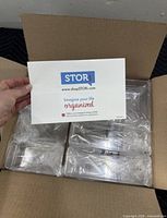 Open carton showing three sealed STORi organizer sets and insert
