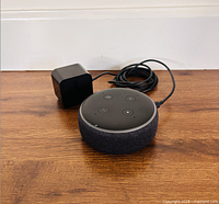 Echo Dot smart speaker with attached power adapter on floor