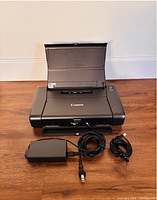 Printer open with feeder raised, power adapter and USB cable shown