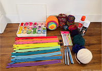 Group shot of embroidery floss organizer, yarn, zippers, crochet hooks, sprays and buttons