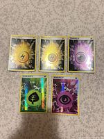 Group shot of five holo energy Pokémon cards