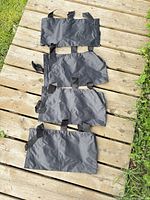 Four black nylon sandbags laid out on wooden surface