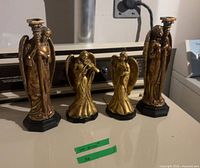 Front view of four gold-tone angel figurines lined on appliance