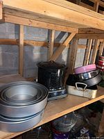 Shelf with stacked cake pans, enamel pot, muffin tray, springform and loaf pans