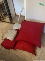 Group view of red pillows, blanket, gray throw, striped sheets