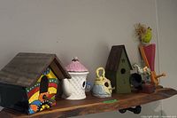 Group view of all birdhouses and music boxes on shelf