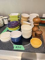 Grouped view showing bowls, ramekins, rectangular bakers and two wooden mills on stovetop