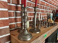 Three tall candlesticks, small holders along shelf
