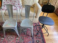 Two metal stacking chairs and one black swivel task chair
