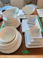 overall view of assorted white round and square plates, bowls and platters on table