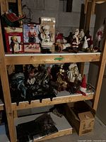 Shelf showing multiple Santa figurines, sleigh, boxed figures, reindeer candleholders and ornaments