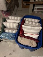 Two bins containing multiple decorative pillows