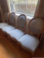 Four matching dining chairs lined up by window