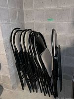 stack of eight black metal folding chairs with light gray padded seats and backs