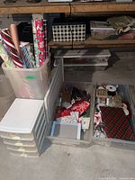 Wide view showing rolls of wrapping paper, plastic drawer tower, two clear bins with contents