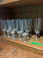 Group of 16 clear stemmed glasses on shelf
