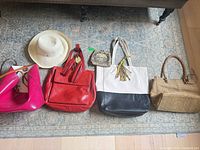 Group shot of all handbags, coin purse and hat on rug