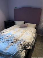 Complete bed showing upholstered headboard and metal frame with bedding removed partially
