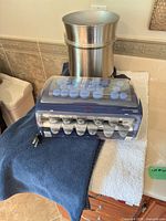 All items grouped: hot roller set, steel bin, blue towel, white mat