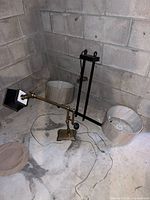 Brass desk lamp, black metal fixture frame, two beige lamp shades on concrete floor