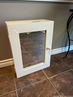 Front view of white wooden cabinet with mirror and knob