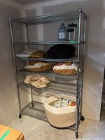Full view of five-shelf metal wire rack on wheels with contents present for scale