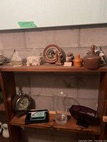 Overall view of shelf showing figurines, clock, vase, bowl and other small decor