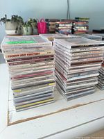 Two tall stacks of CDs showing spines with titles such as Bing Crosby Christmas Collection and Country Heat Christmas