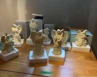 Full set of eight ivory angel figurines on table with boxes behind