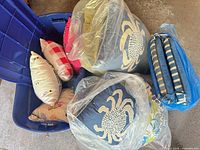 Overall lot in tote showing blue bin, crab pillows, striped cushion and assorted smaller pillows