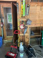 Wall with saws, levels, watering can, spool, pressure washer, sprayer, reel mower, paint can