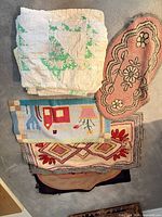 Stack showing white/green/yellow quilt atop three small rugs