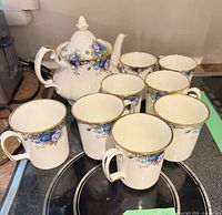 Teapot with lid plus seven mugs on stovetop