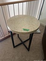 Full view of round sea shell top side table with metal base