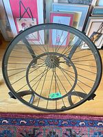 Top view of metal side table showing glass surface and bicycle wheel rim/spokes beneath