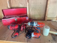 Group shot of all items: toolbox, Benchmark drill, Black+Decker drill with battery and charger, mallet