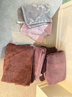 Stack of mauve and lavender bath towels with separate grey and pink hand towels
