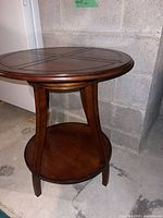 Full view of round wooden side table showing top and shelf