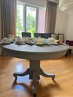 Full view of round grey table with pedestal base and casters