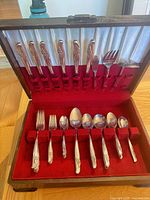 Open wooden chest showing knives in lid slots, serving utensils, lower tray forks and spoons