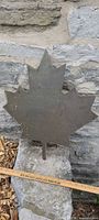 Front view of metal maple leaf on stone wall
