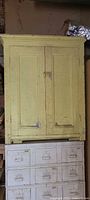 Front view of yellow wooden cupboard sitting atop another unit