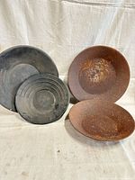 Group shot of two rusted steel and two black plastic gold pans
