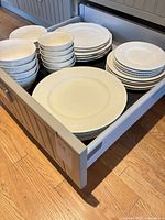 Drawer containing stacked white Bowring porcelain dinnerware: dinner plates, salad/dessert plates and bowls