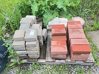 Overall view of stacked red bricks and concrete pavers on pallet