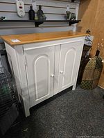 front view showing white body, two doors with ceramic knobs, natural wood top