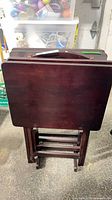 Set of four wooden folding TV trays stored in matching stand